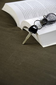 Car keys placed beside a book with a cloth backdrop